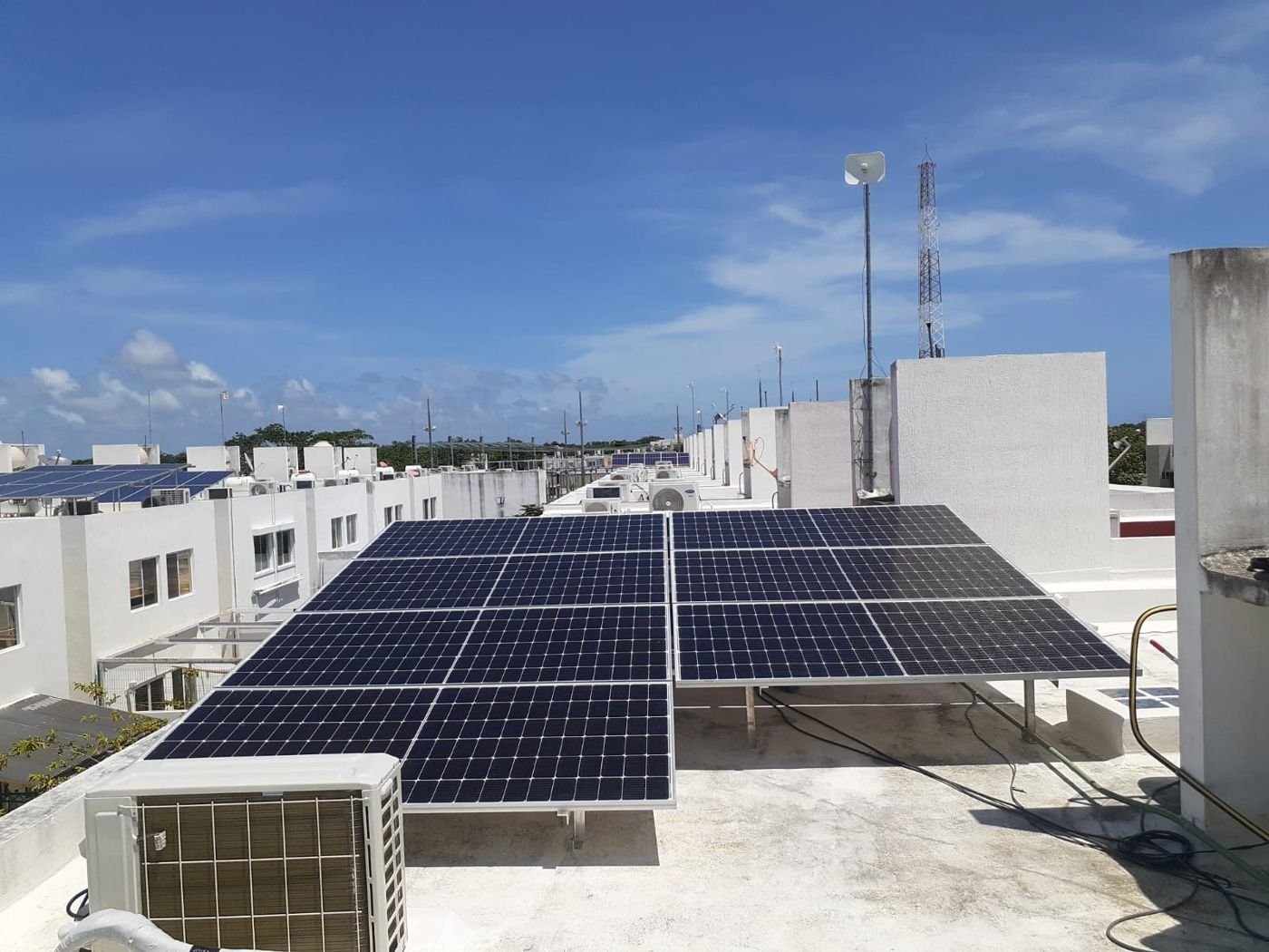 Arreglo de paneles solares instalado en la azotea de una vivienda en un conjunto residencial